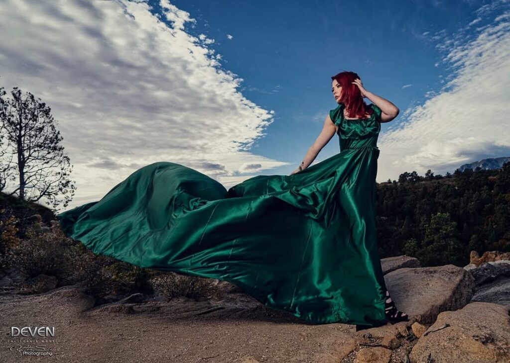 Deven Skye in a flowing emerald gown on a mountain ridge